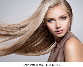 Face of the Beautiful young woman with long straight  hair - posing at studio over gray background