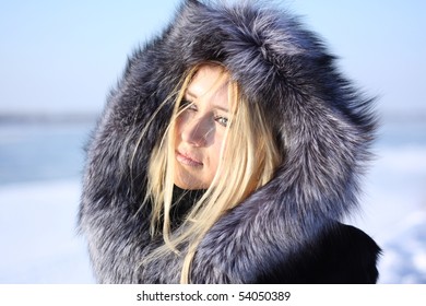 face beauty girl with blonde hair outdoors, in a fur coat, River in the background