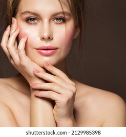 Face Beauty Woman. Model With Full Plump Glossy Lips And Smooth Skin Holding Hands With Nude Nail Polish On Cheek Over Dark Background