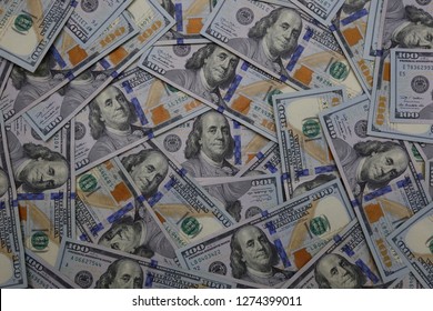 The Face Of Benjamin Franklin, Shown On The Front Of The U.S. $100 Bill, Is Shown Among Other Loosely Scattered Bills Of The Same Denomination In An Overhead View.