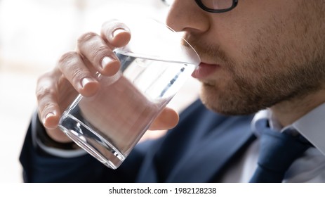 Face of business man holding glass and drinking fresh pure still water during work. Male employee keeping healthy hydration, feeling thirsty. Healthcare, refreshment, good habit concept. Close up - Powered by Shutterstock