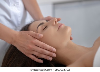 Face care. Young pretty woman lying and having face massage