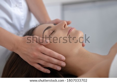 Face care. Young pretty woman lying and having face massage