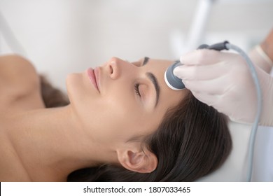 Face care. Young woman lying down with eyes closed during professional beauty procedures
