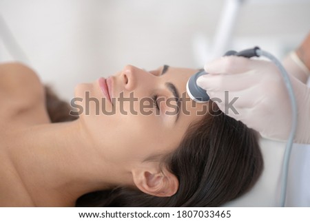 Face care. Young woman lying down with eyes closed during professional beauty procedures