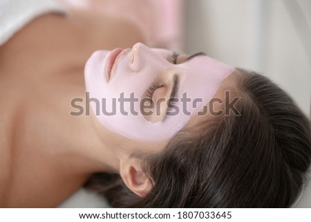 Face care. Young woman lying down with a mask on her face