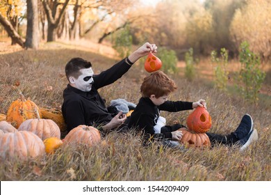 A Face Carved In An Orange Pumpkin. Halloween Deco. Father And Son Skeletons