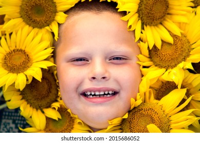 The face of a child boy in sunflower colors. Close-up portrait of a boy in sunflower flowers.