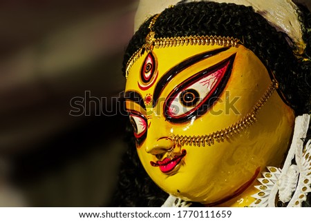 Face of a clay idol of Goddess Devi Durga in a dark black background,  before upcoming Durga Puja