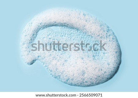 Face cleanser mousse or shampoo sample on light blue background. Soap foam texture swatch close up.