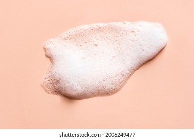 Face cleansing mousse sample. White cleanser foam bubbles on nude background. Soap, shower gel, shampoo foam texture closeup.