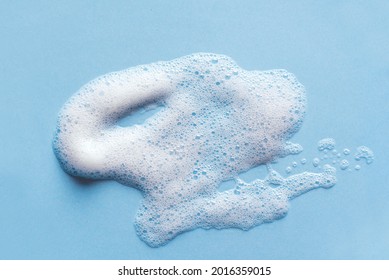 Face Cleansing Mousse Sample. White Cleanser Foam Bubbles On Blue Background. Soap, Shower Gel, Shampoo Foam Texture Closeup.