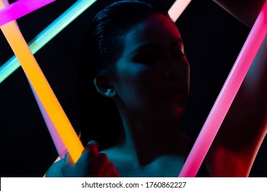 Face Close Up Of High Fashion Trend Cosmetic Make Up With NEON Tube Light, Effect On Skin Of Young Asian Woman In Low Exposure, Express Feeling By Color Of LED Line, Copy Space Black Backgrounds