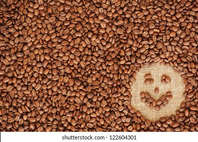 face coffee frame made of coffee beans on burlap texture