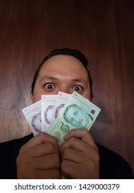 Face With Emotion Expression Of A Young Man And Holding Singaporean Banknotes