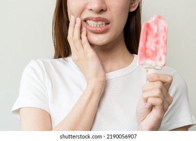 Face expression suffering from sensitive teeth, Asian young woman touching cheek