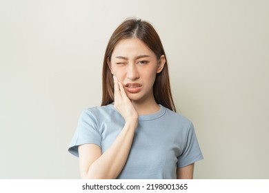 Face expression suffering from sensitive teeth, Asian young woman touching cheek - Shutterstock ID 2198001365