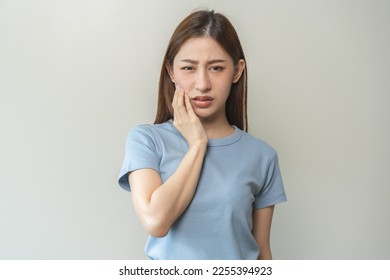 Face expression suffering from sensitive teeth and cold, asian young woman, girl feeling hurt, pain touching cheek, mouth with hand. Toothache molar tooth, dental problem isolated on white background. - Shutterstock ID 2255394923