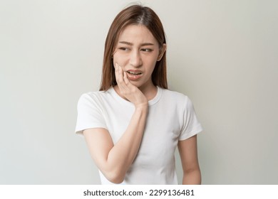 Face expression suffering from sensitive teeth, Asian young woman touching cheek