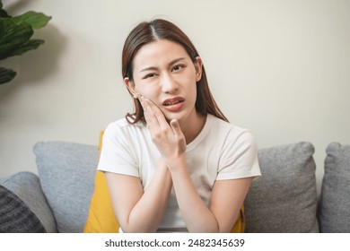 Face expression suffering from sensitive teeth, Asian young woman touching cheek