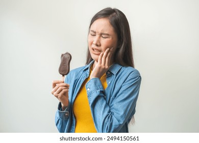 Face expression suffering from sensitive teeth and cold, asian young woman touching cheek, hurt or pain eating ice cream with chocolate. Toothache molar tooth, dental problem isolated on background.