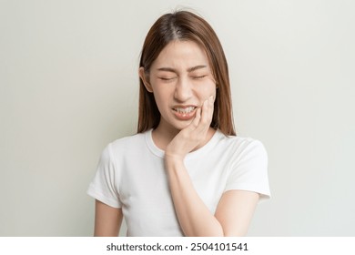 Face expression suffering from sensitive teeth, Asian young woman touching cheek