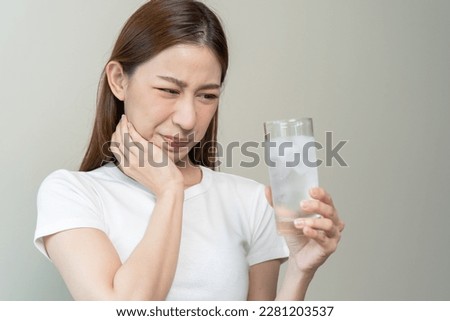 Face expression suffering from sensitive teeth, Asian young woman touching cheek