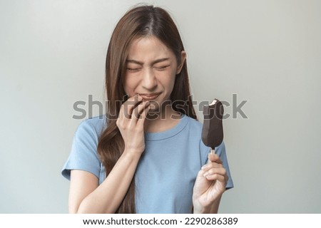 Face expression suffering from sensitive teeth and cold, asian young woman, girl feeling hurt, pain eating ice cream, lolly. Toothache molar tooth at home, dental problem isolated on white background.