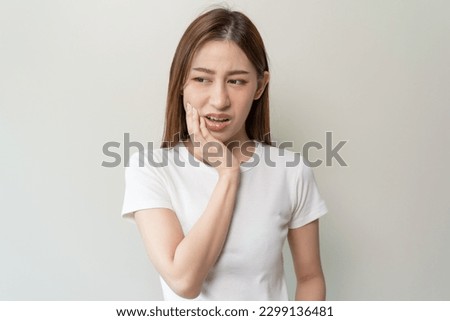 Face expression suffering from sensitive teeth, Asian young woman touching cheek