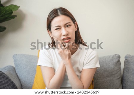 Face expression suffering from sensitive teeth, Asian young woman touching cheek