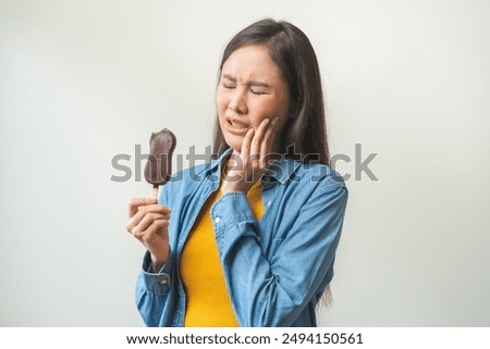 Face expression suffering from sensitive teeth and cold, asian young woman touching cheek, hurt or pain eating ice cream with chocolate. Toothache molar tooth, dental problem isolated on background.