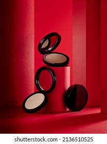 Face highlighter compact makeup powder  cases with mirror. Cosmetic products advertisement on red decorative background with decorated tubes - Shutterstock ID 2136510525