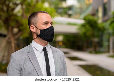 Face of Hispanic bald businessman thinking and wearing mask in the city with nature - Powered by Shutterstock