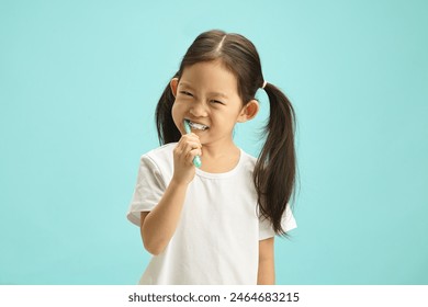 Face of Japanese child girl cleaning mouth with a brush for morning routine and oral self care. Happy asian ethnicity kid using toothbrush standing over blue isolated background with free copy space. - Powered by Shutterstock