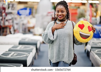 Face Love Heart Emoji. African Woman With Pillow In A Modern Home Furnishings Store.