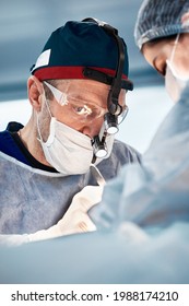 The Face Of A Male Surgeon During The Operation, Close-up Head Light, A Doctor In A Mask, Glasses Makes A Life-saving Operation