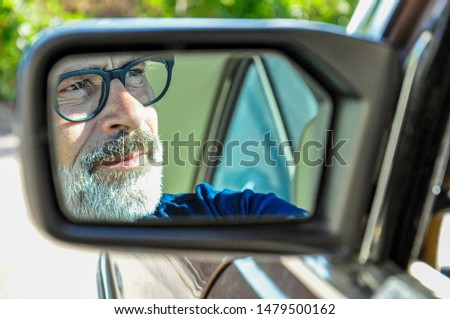Face of a man in the outside mirror of his vintage car