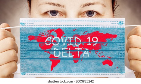 Face mask in hand with world map and inscription COVID 19 DELTA . Delta variant outbreak around the world