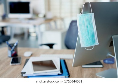 Face Mask Hanging On Computer Screen In An Empty Office