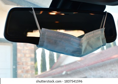 Face Mask Haning From A Rear View Mirror In An Automobile.
