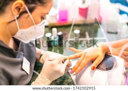 With face mask painting colored nails of the client. Reopening after the corod-19 pandemic. Manicure and Pedicure Salon. Coronavirus