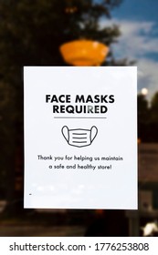 Face Mask Required Sign On Door Of Store With Reflection Of Sky And Trees Around It And Bug Crawling On It