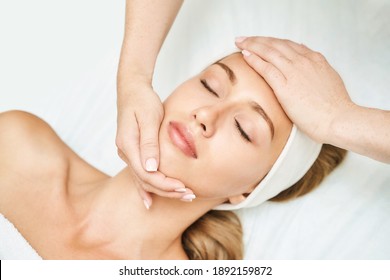 Face massage at spa salon. Doctor hands. Pretty female patient. Beauty treatment. Healthy skin procedure. Young woman head. Light background. Scrub rejuvenation. Facial dermatology mask. Detox therapy - Shutterstock ID 1892159872