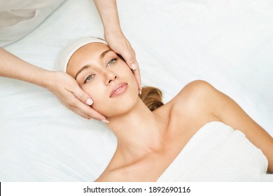 Face massage at spa salon. Doctor hands. Pretty female patient. Beauty treatment. Healthy skin procedure. Young woman head. Light background. Scrub rejuvenation. Facial dermatology mask. Detox therapy - Shutterstock ID 1892690116