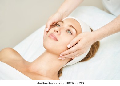 Face massage at spa salon. Doctor hands. Pretty female patient. Beauty treatment. Healthy skin procedure. Young woman head. Light background. Scrub rejuvenation. Facial dermatology mask. Detox therapy - Shutterstock ID 1893955720