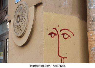 The face is painted on the wall of an old town house with a molded round relief. Urban