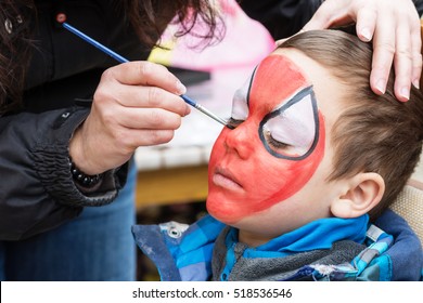 Face painting artist painting child as spider man 