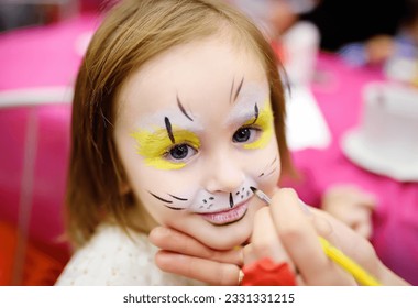 Face painting for cute little gorl during kids merriment. Face paint for "Animals" theme on birthday party. Preschooler kids celebrating party in entertainment center. Child in amusement park - Powered by Shutterstock