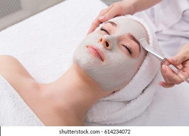 Face peeling mask, spa beauty treatment, skincare. Woman getting facial care by beautician at spa salon, side view, close-up