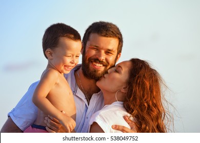 Face Portrait Of Hugging Beautiful Family - Happy Mother, Father Holding Baby Son On Hands Walk With Fun On Sunset Beach. Active Parents, People Outdoor Activity On Tropical Summer Holiday With Child